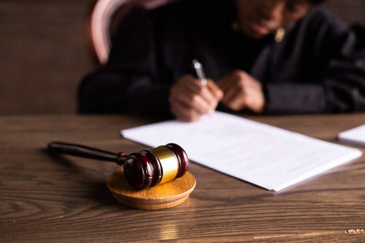 gavel-in-foreground-person-writing-in-background gavel-in-foreground-person-writing-in-background